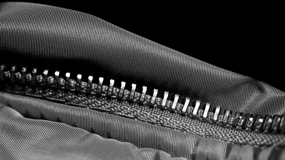 Close-up of a zipper on a textured textile fabric, showcasing design elements.