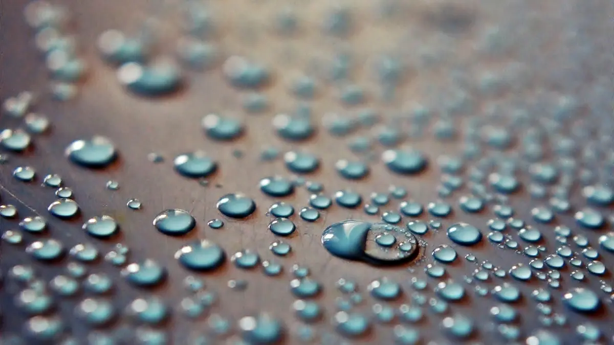 Close-up of droplets on a textured surface, demonstrating a water-repellent effect.