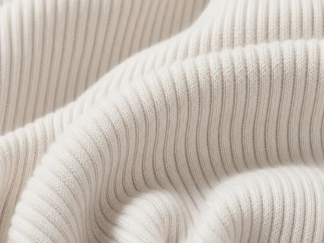 Close-up of soft white ribbed fabric folded into overlapping, gently curved layers.