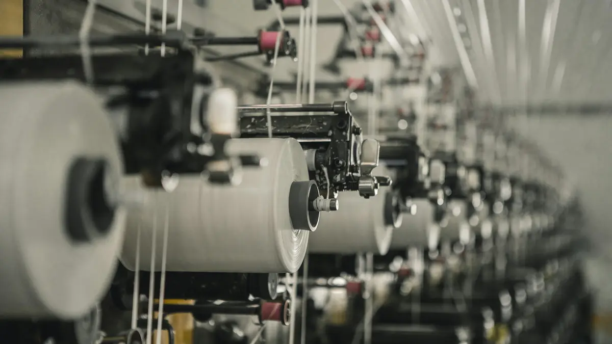 Spools of thread in a textile production facility, showcasing multiple machines in operation.