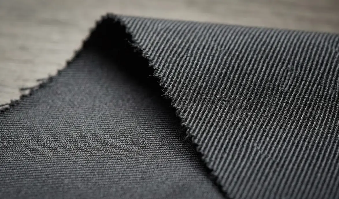 Close-up of two dark gray textiles showing distinct ribbed woven and fine knit surface structures.