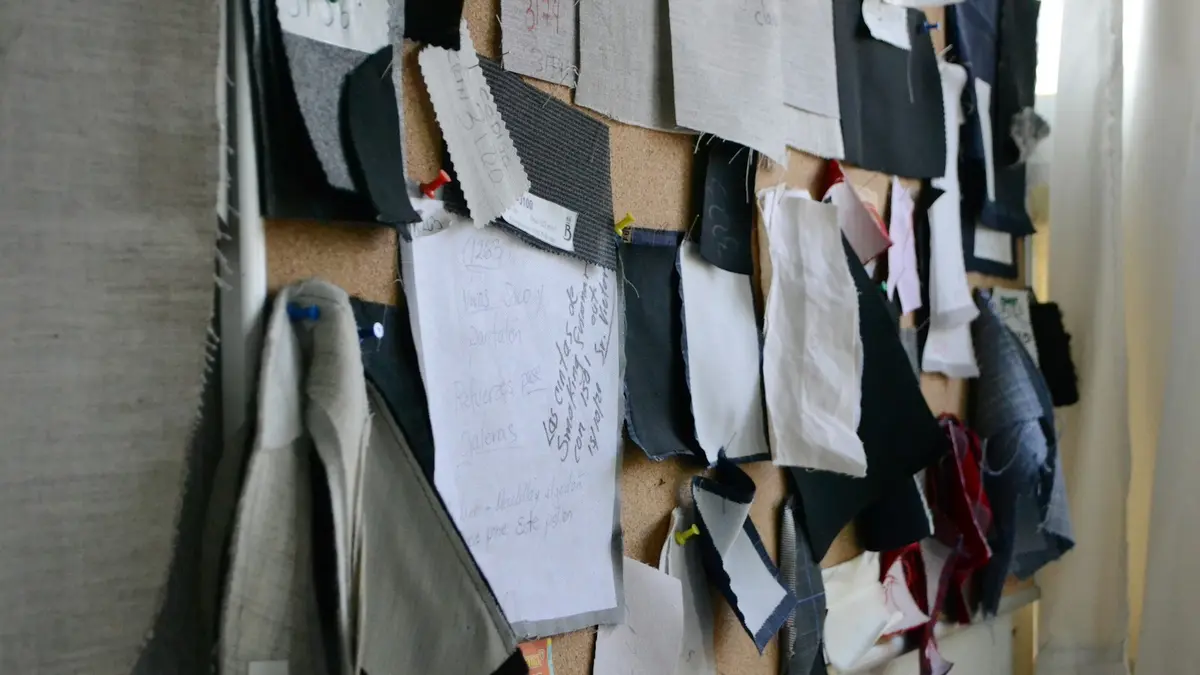 Textile samples and notes pinned to a corkboard, showcasing various fabric pieces and patterns.